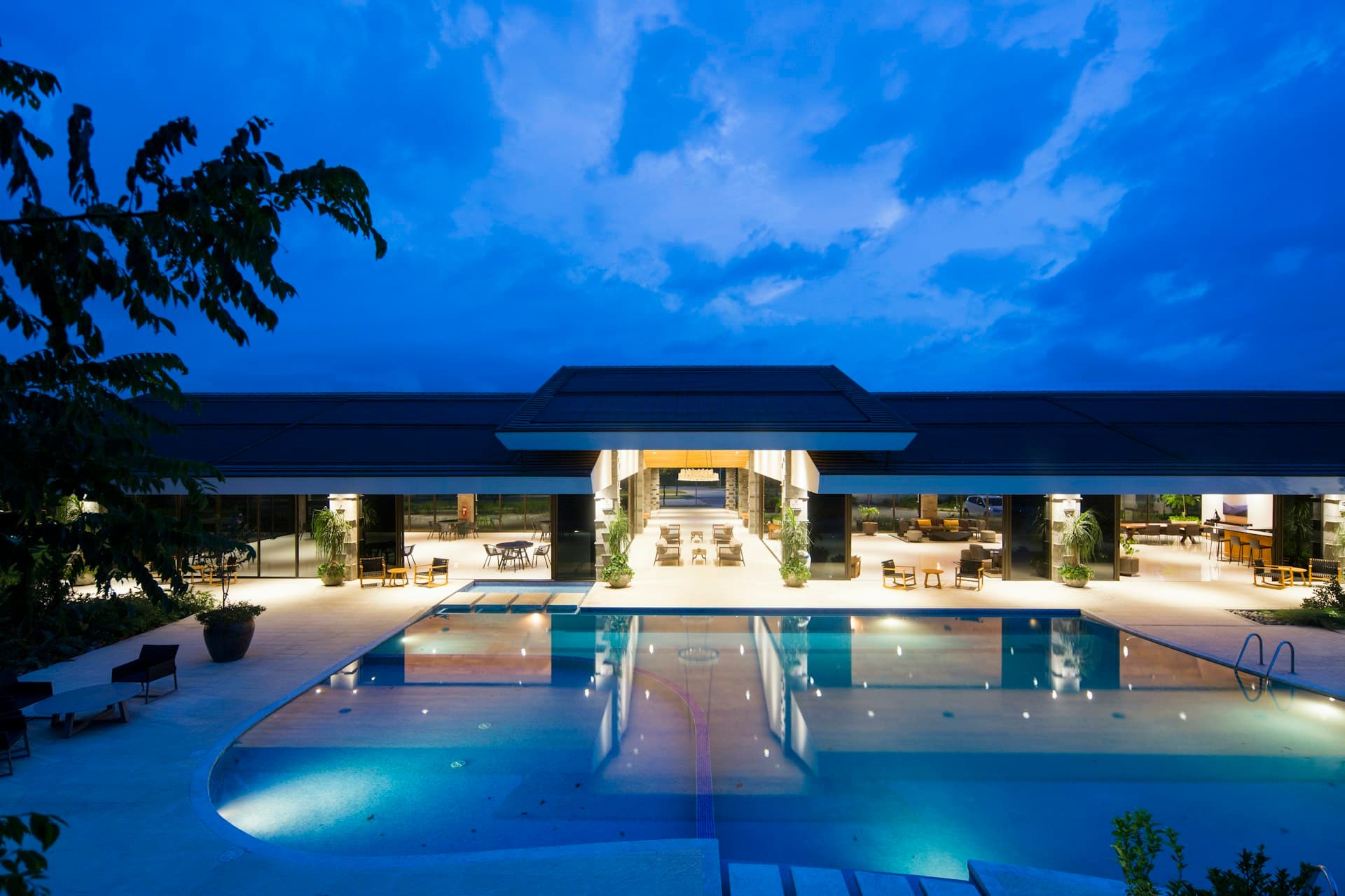Contemporary hotel resort exterior with pool and evening lighting