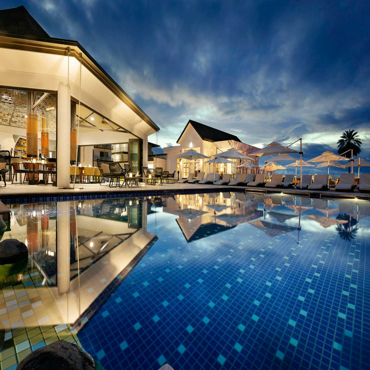Luxury resort exterior at dusk with tropical landscaping and warm lights