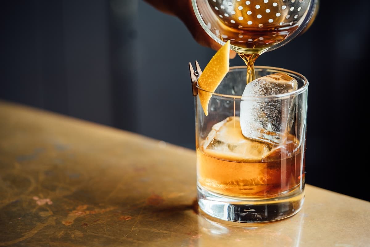 Glass of amber cocktail on a bar with soft bokeh lights